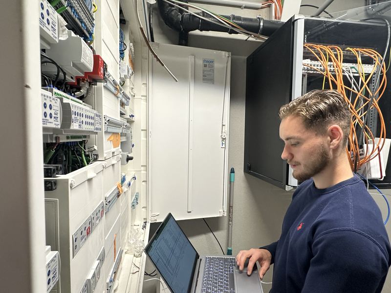 Erik Jeschke programmiert mit dem Laptop eine KNX-Anlage am geöffneten Verteilerschrank
